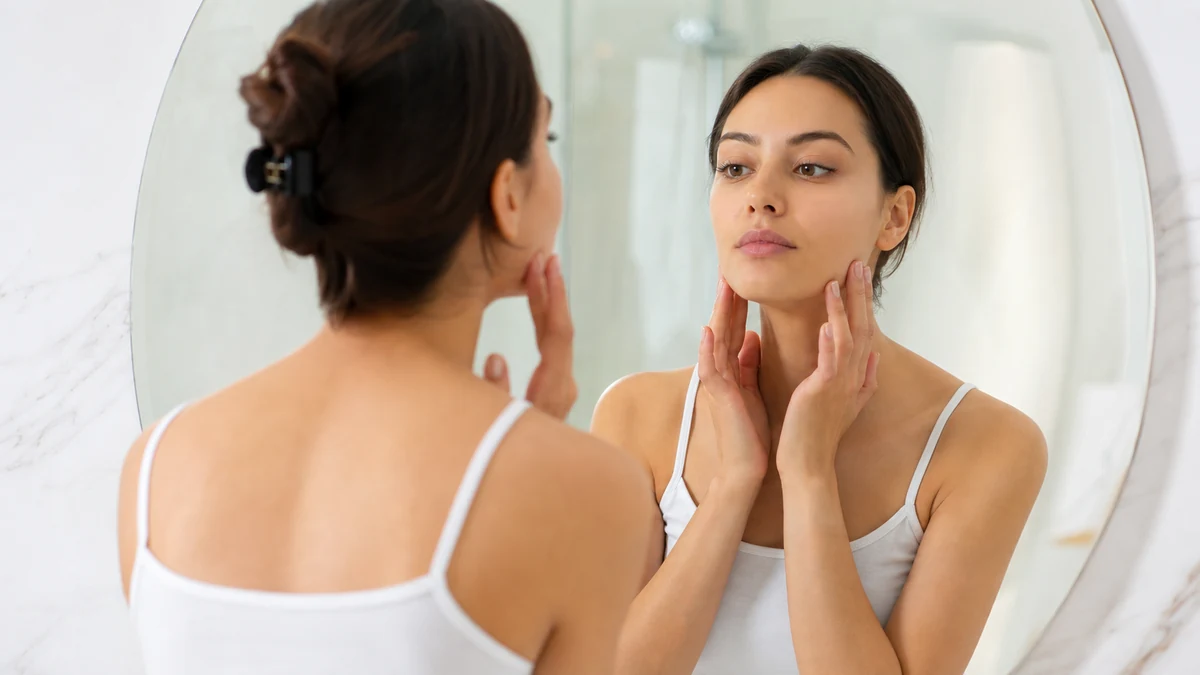 Checking face shape in a mirror with hair pulled back